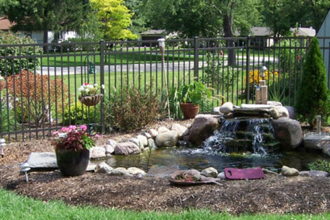 A serene backyard pond with a waterfall and rocks in Batavia, IL