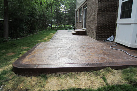 Concrete patio with a brick wall in Batavia, IL, showcases a blend of textures and outdoor living space