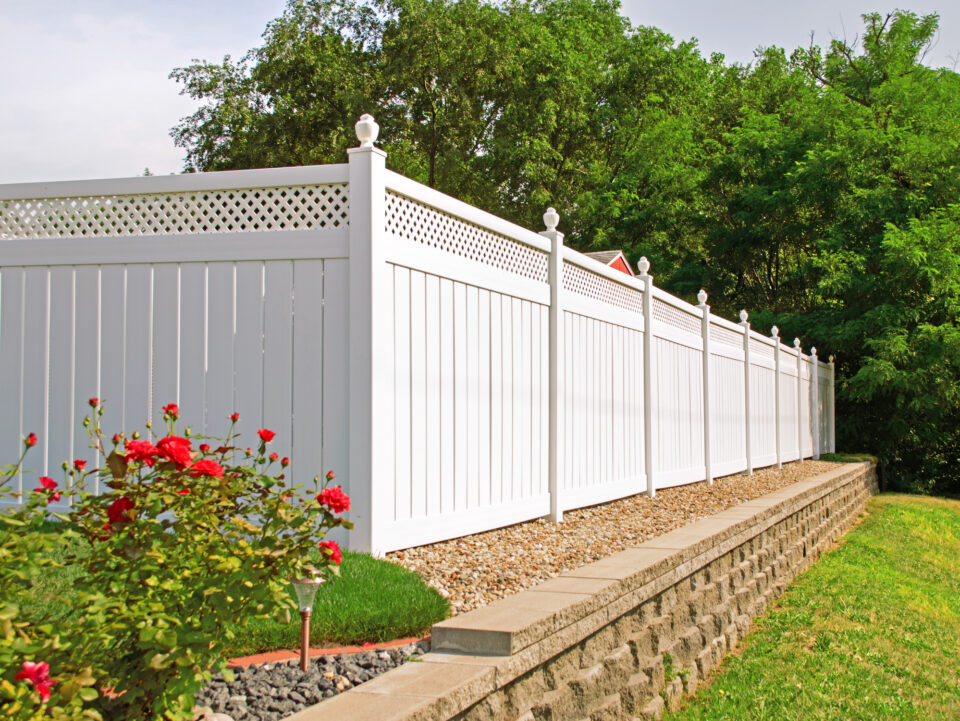 White fence and stone wall with blooming flowers, captured in Batavia, IL