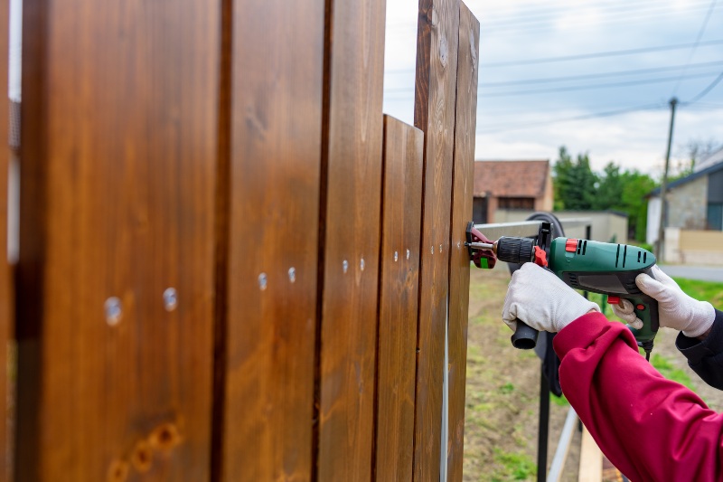 Man installing wooden fence boards with power drill in Chicago, IL
